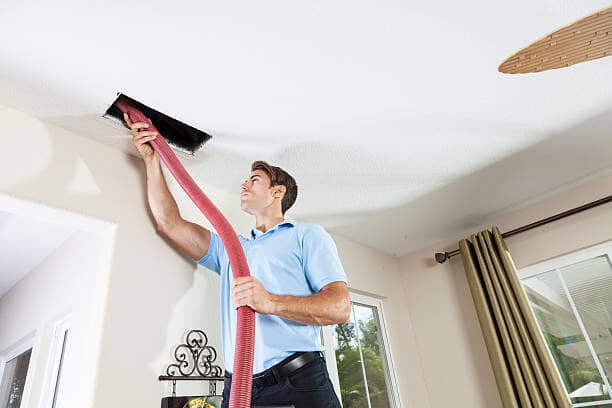 Air duct cleaning technician working inside Huntington home system