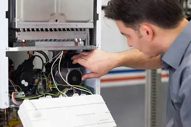 Technician checking hot-water piping connected to a tankless water heater in Winfield, WV.